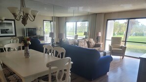 Ein großzügiges Wohnzimmer mit Essbereich, großen Fenstern und Blick ins Freie.