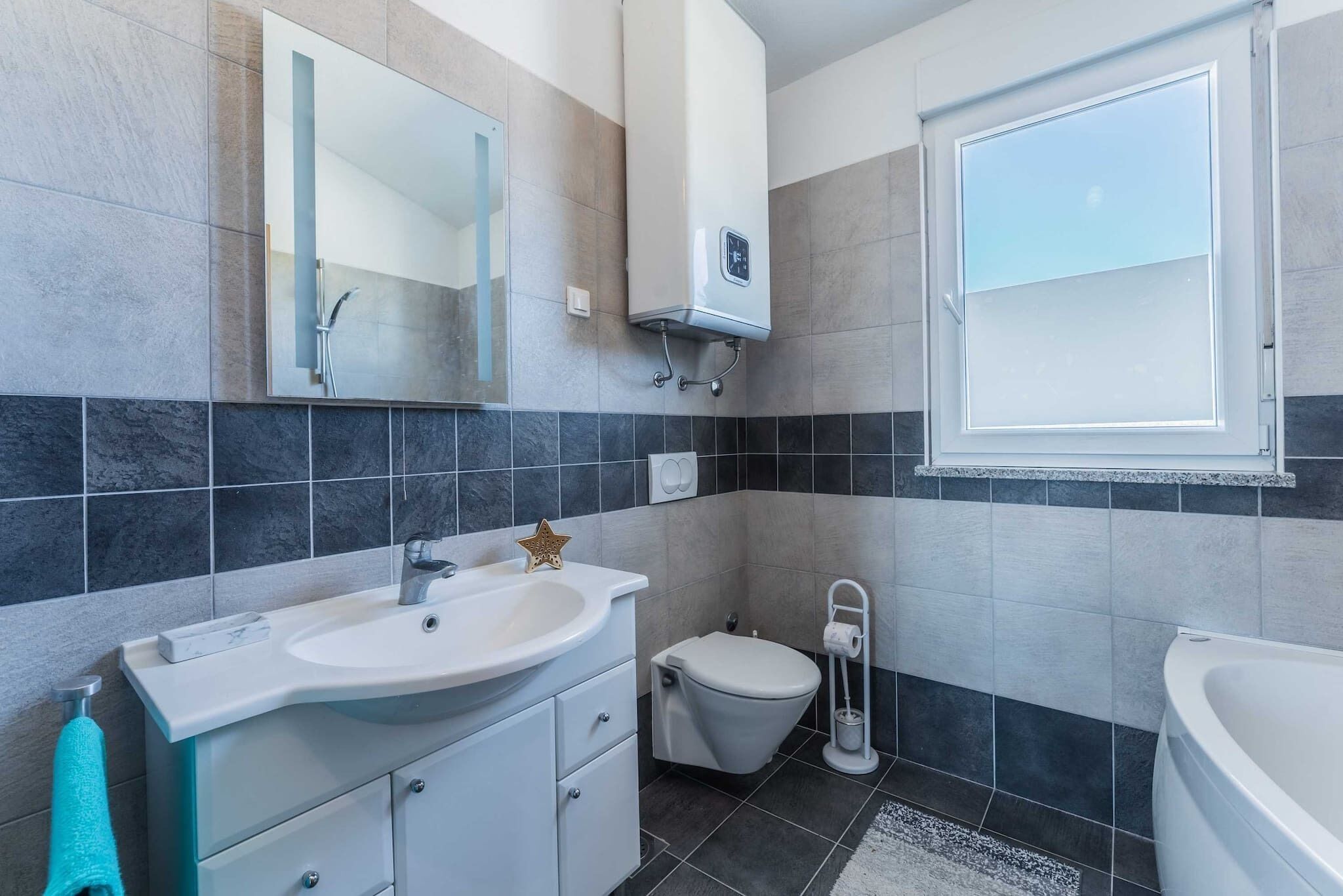 A modern bathroom with a sink, toilet, and bathtub.