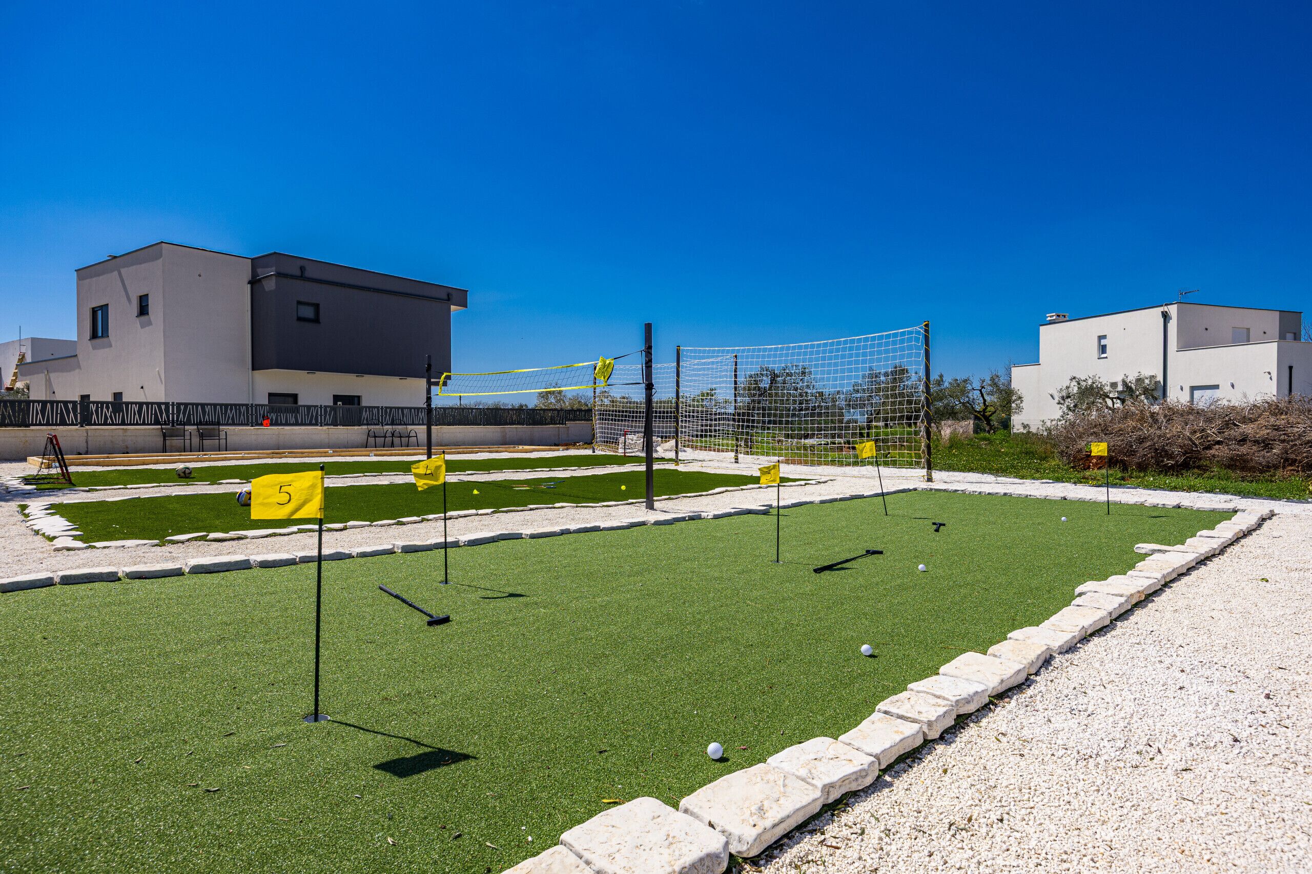 A mini-golf course with a clear path, a net, and numbered flags.