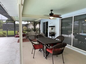 An outdoor patio with a dining table, chairs, and a ceiling fan.