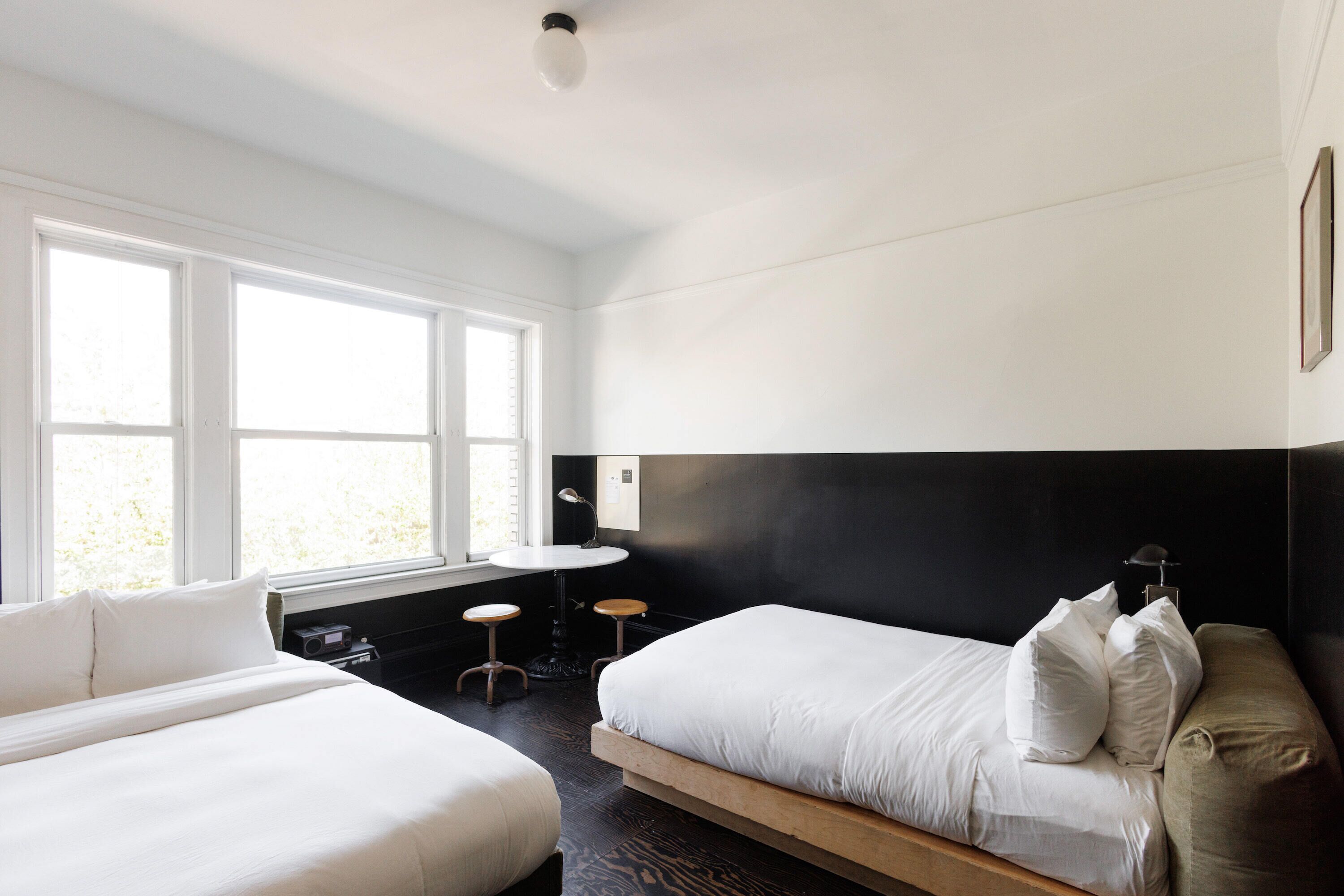 A modern bedroom with two beds, a small table, and a window.