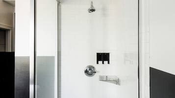 Une salle de bain moderne avec une douche à parois de verre, des murs recouverts de carreaux blancs et un banc en bois.