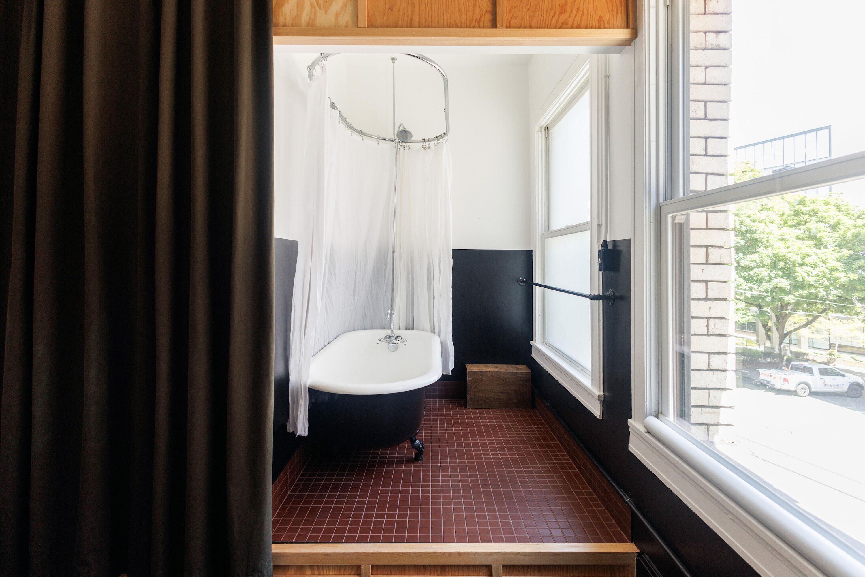 A bathroom with a bathtub, a shower curtain, and a window.