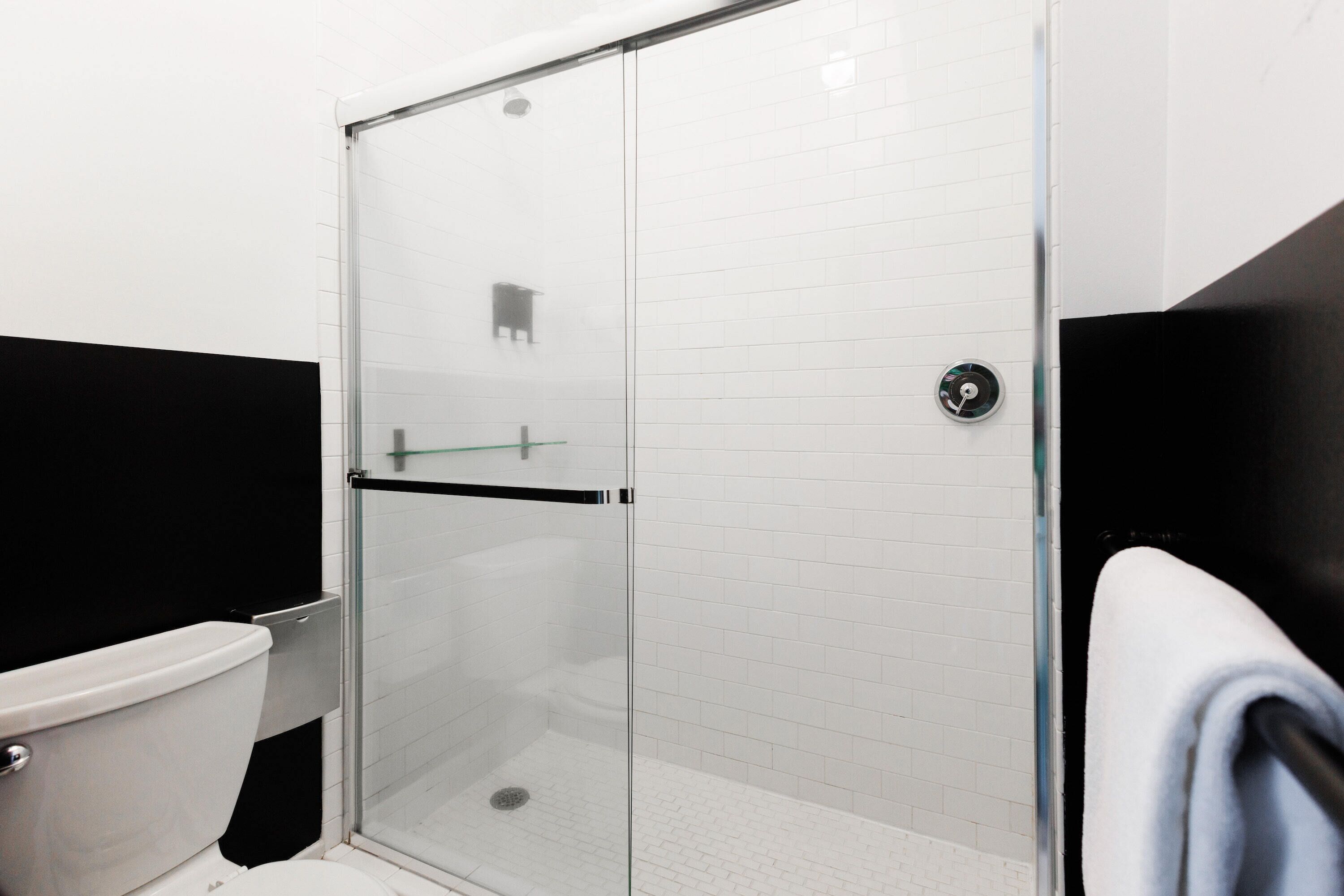 A modern bathroom with a glass shower enclosure, a toilet, and a towel rack.