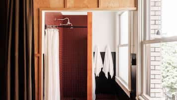 Un baño con ducha de azulejos rojos, armarios de madera y ventana con vistas a la vegetación.