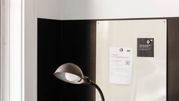 A laptop on a marble table, a coffee mug with the word "kasa" on it, a desk lamp, and a bulletin board with a welcome sign and a business card.