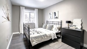 A bedroom with a bed, bedside table, and a dresser. - Unique, Converted Bakery In Historic Highlands (Edmonton)
