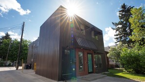A two-story building with a metal exterior and a glass door entrance. - Unique, Converted Bakery In Historic Highlands (Edmonton)