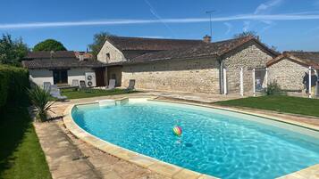 Une piscine avec une maison en pierre en arrière-plan.