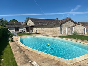 A swimming pool with a stone house in the background.
