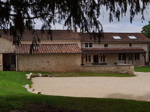 A two-story stone building with a tiled roof, a covered porch, and a gravel driveway. - Sleeps 13/15, 270 m2 house with swimming pool / CHEQUES ANCV ACCEPTES (Bonnes)