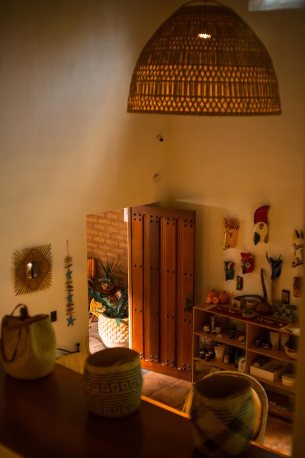 A room with a wooden door, a hanging light fixture, and various wall decorations including masks. - La Paranera Hotel & Relax (Comala)