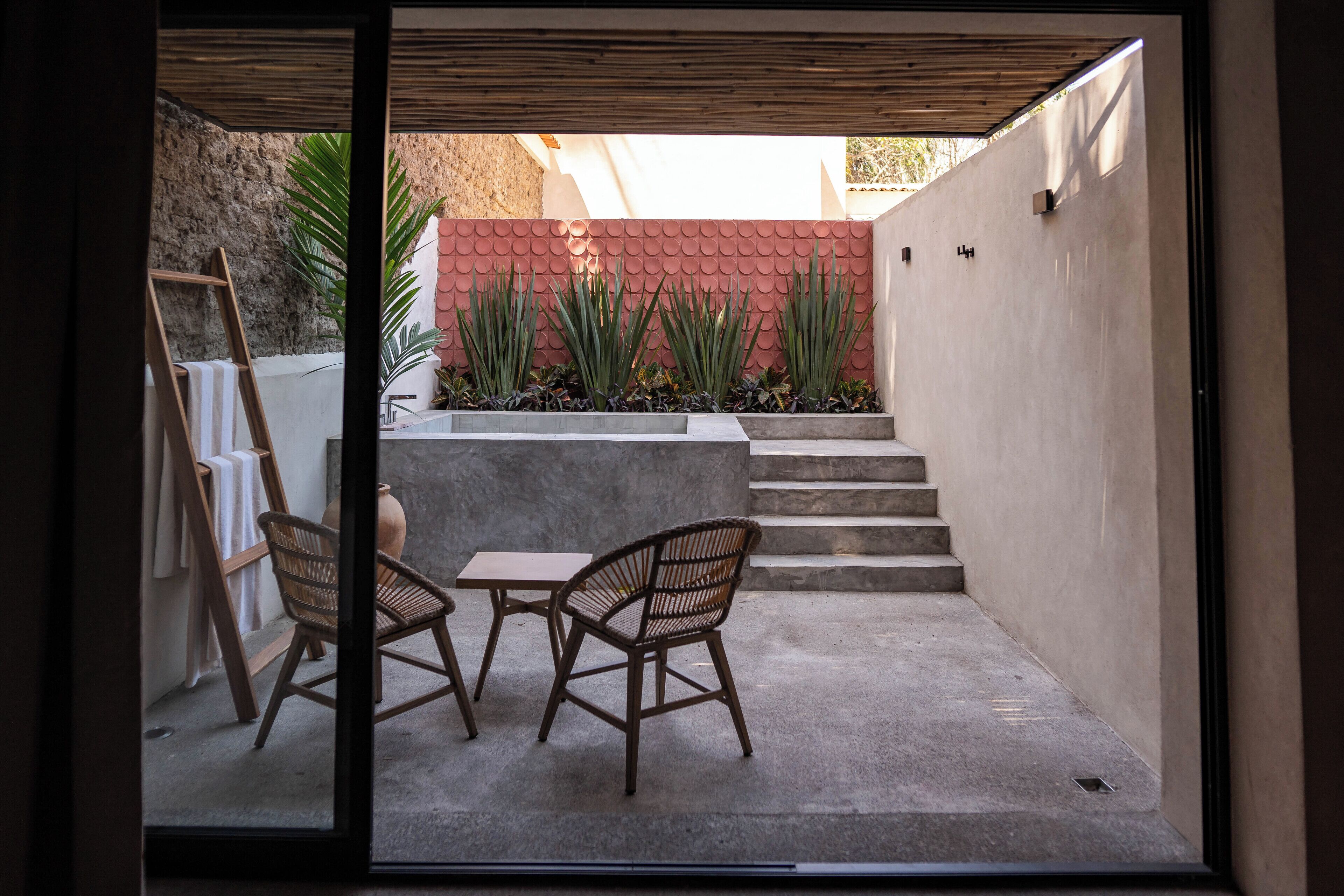 A patio with a table and chairs, a ladder, and a wall with a textured pattern.