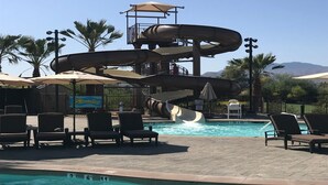 Una piscina con tobogán de agua, sillas de descanso y un letrero que dice 'Skywinderm'.