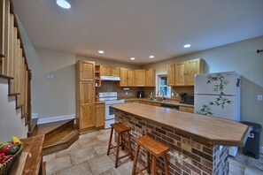 Une cuisine avec des meubles en bois, un grand îlot central et un réfrigérateur orné de motifs floraux.