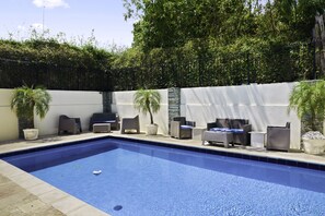Una piscina con sillas de descanso y plantas en macetas.