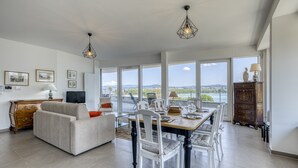 A spacious living area with a dining table, white chairs, a sofa, and a view of the outdoors. - La Cantonade 4* - Breathtaking view of Lake Annecy (Annecy)