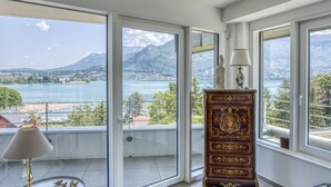 A room with a view of a lake and mountains, a wooden cabinet, and a lamp. - La Cantonade 4* - Breathtaking view of Lake Annecy (Annecy)