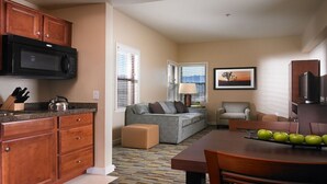 A compact living space with a kitchenette, a grey sofa, a small table with apples, and a television. - Westin Desert Willows, Palm Desert (Palm Desert)