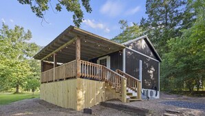 Une cabane en bois dotée d’une terrasse et d’un escalier menant à un porche abrité.