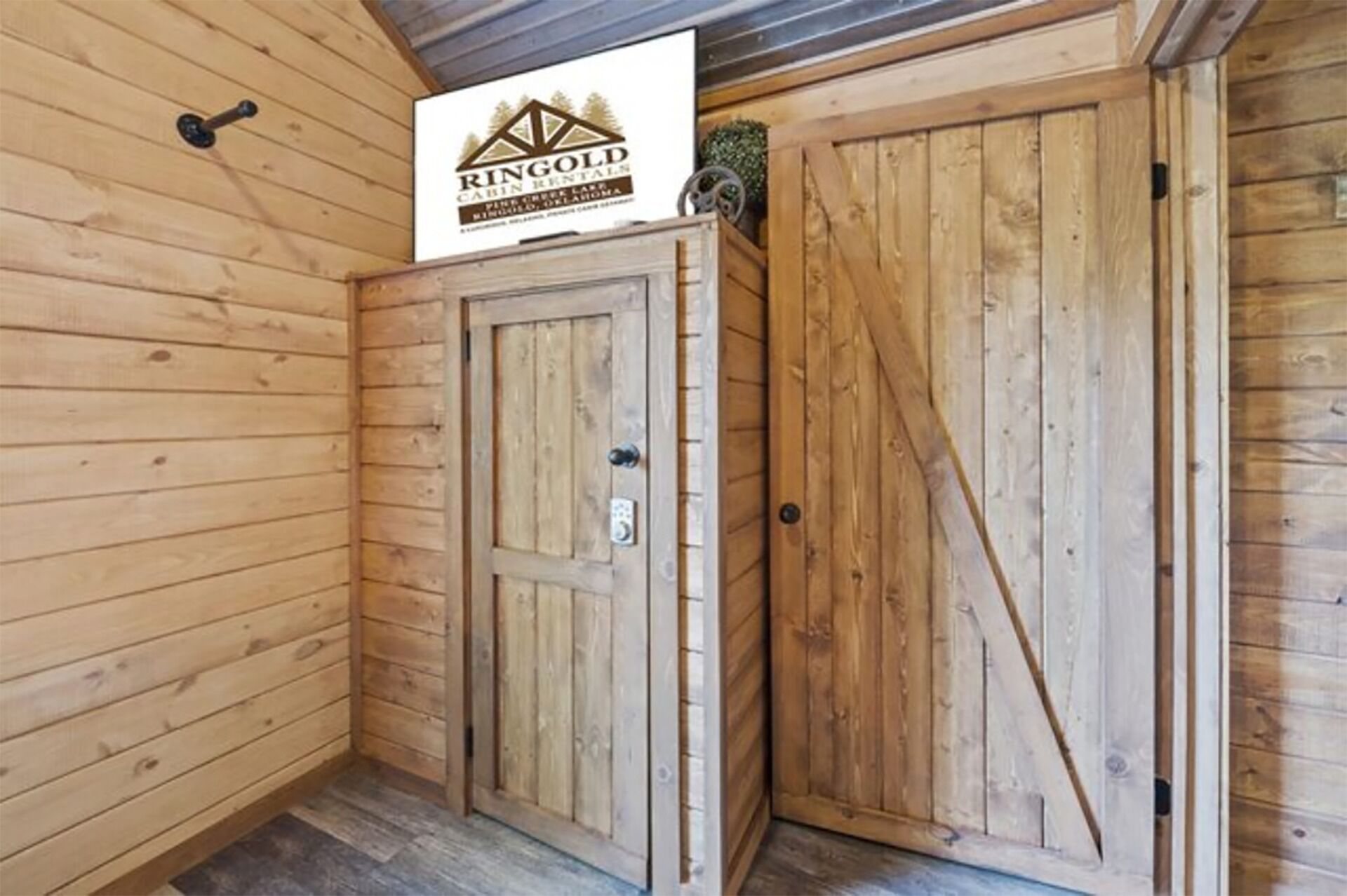 Interieur van een houten hutje met een bordje voor Ringold Cabin Rental, met twee houten deuren en een klein raam.