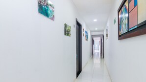 A long, narrow hallway with white walls and a tiled floor. There are several doors along the hallway, each marked with a number. - Hotel Guajira Azul (Riohacha)