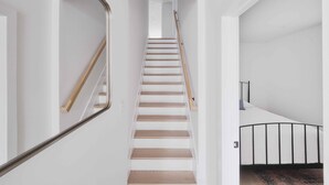 Una escalera de madera con barandilla de metal que conduce a una plataforma con pasamanos negro.