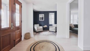 Una sala moderna con una pared de acento oscura, dos sillones, una mesita y un tapiz grande tejido.