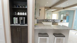 Eine moderne Küche mit dunklen Schränken, einer Kaffeemaschine und einer Arbeitsplatte aus Granit.
