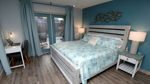 Ein Schlafzimmer mit Bett, Schreibtisch, Stuhl und Blick ins Freie.