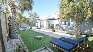 Ein Garten mit Pool, Liegestühlen und einer Terrasse.