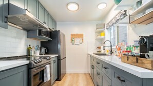 Une cuisine moderne dotée d’appareils électroménagers en acier inoxydable, de planchers en bois et de meubles de couleur claire.