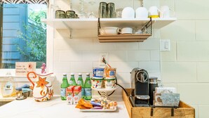 Une cuisine avec des meubles blancs, une machine à café et divers ustensiles de cuisine sur le plan de travail.