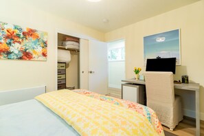 Un dormitorio con cama, escritorio, silla, televisor y armario.