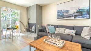 Un salon moderne avec un canapé gris, une table basse en bois et une cheminée.