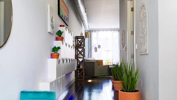 Un pasillo con un banco color turquesa, plantas en macetas y una escalera que lleva a otra habitación.