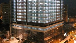 A multi-story building with numerous illuminated windows, likely a hotel or office building, surrounded by a parking area and other structures. - Polana Plaza Hotel (Maputo)