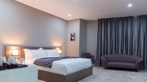 A hotel room with a bed, bedside table, lamp, chair, and curtains. - Polana Plaza Hotel (Maputo)