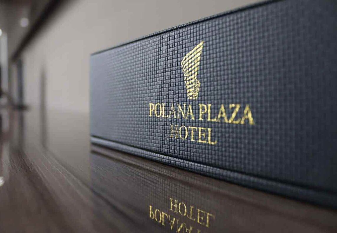 A dark blue sign with the text "POLANA PLAZA HOTEL" in gold lettering.