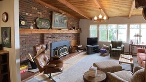 Una sala acogedora con chimenea de ladrillo, un sillón de cuero y televisor.