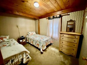 Quarto com duas camas, uma cômoda e um espelho.