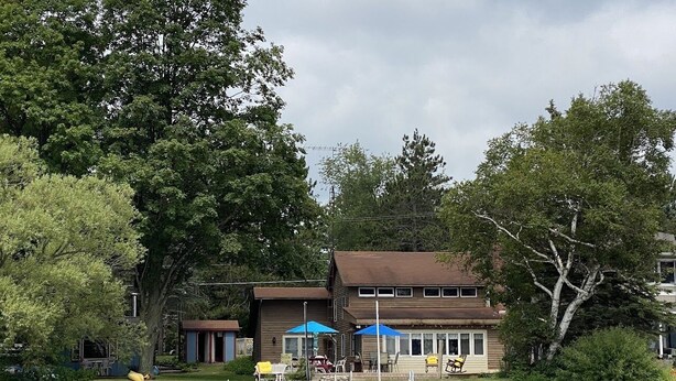 Una propiedad frente al lago con muelle, mobiliario exterior y un edificio de techo marrón.