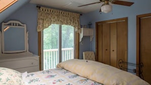 A bedroom with a bed, a ceiling fan, a window with a view, a dresser, and a wardrobe. - Two bedroom upstairs unit. "Timberlane Mountain Retreat" with mini kitchen (Boone)