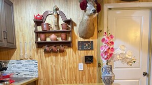 A kitchen with wooden walls, a mounted deer head, a clock, and a vase with flowers. - Cottage Americana at Coco Ranch (Ocklawaha)