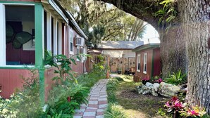 A pathway leading to a row of cabins with a large tree arching over the path. - Cottage Americana at Coco Ranch (Ocklawaha)