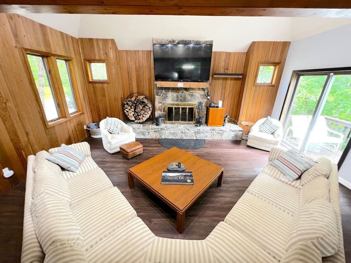A cozy living room with a fireplace, two sofas, a coffee table, and a TV.