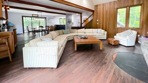 A spacious living room with a large sectional sofa, a coffee table, and a staircase leading to another level. - Stratton Mountain Home - Hot Tub, Sauna, Fire Pit, & MORE! (Jamaica)