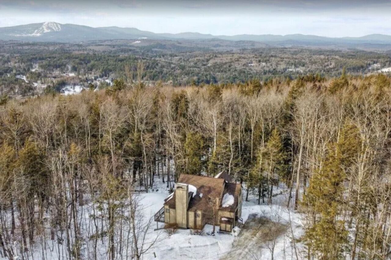 Une cabane située dans une zone boisée, offrant une vue sur les montagnes lointaines.