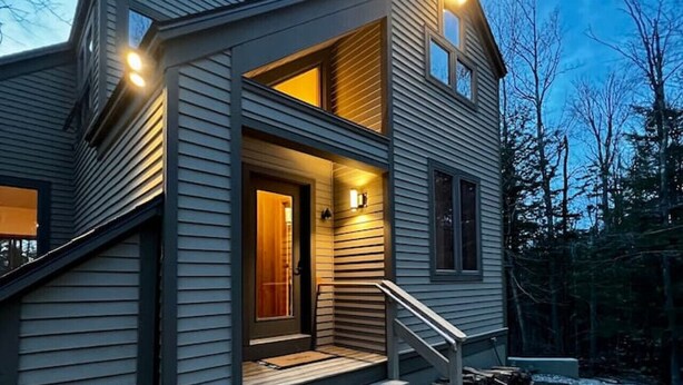 A modern two-story house with a front porch, a staircase, and a driveway. - Stratton Mountain Home - Hot Tub, Sauna, Fire Pit, & MORE! (Jamaica)