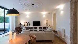 A modern living room with a sofa, TV, and dining area. - Classy & Stylish Porto Duplex (Porto)